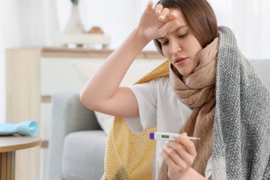 Evde termometresi ve battaniyesi olan hasta genç bir kadın var.