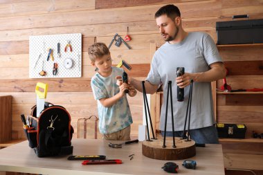 Babası ve küçük oğlu farklı enstrümanlarla atölyede tabure hazırlıyorlar.