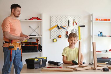 Mutlu babası ve farklı aletlerle evde mobilya montajı yapan küçük oğlu.