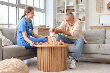 Parkinson sendromu olan yaşlı bir adam ve evde küplerle oynayan bir hemşire.