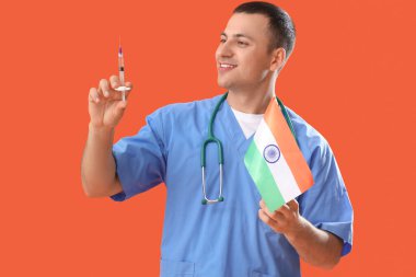 Male nurse with flag of India and syringe on orange background. National Doctor's Day celebration clipart