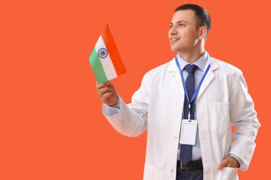 Turuncu arka planda Hindistan bayrağı olan bir erkek doktor. Ulusal Doktorların Günü kutlaması