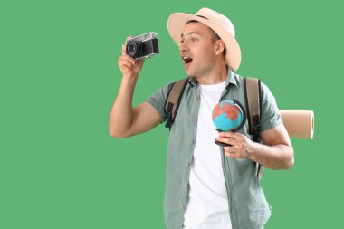 Yeşil arka planda fotoğraf makinesi olan sürpriz bir erkek turist.