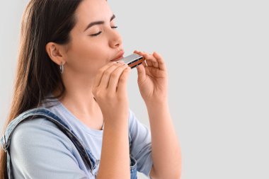 Açık arkaplanda mızıka çalan genç kadın, yakın plan.