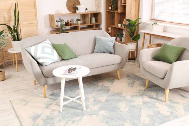 Oturma odasının içinde kanepe, koltuk ve raf üniteleri var.