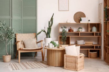 Oturma odasının içinde yeşil katlı ekran, koltuk ve masa.