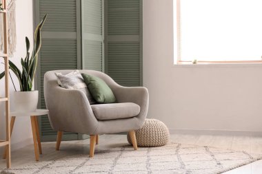 Oturma odasının içi, yeşil katlı ekran, koltuk ve puf