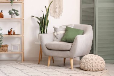 Oturma odasının içinde yeşil katlanan ekran, koltuk ve raf ünitesi