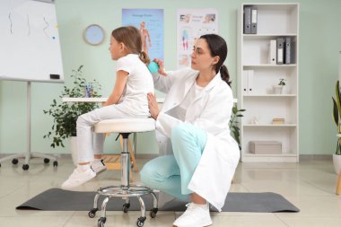 Kadın osteopat klinikte küçük bir hastaya masaj yapıyor.