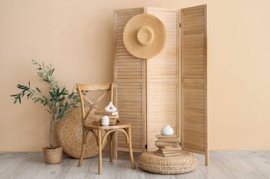 Katlanmış perdeli rahat bir sandalye, bej duvarın yanında sedir ve kitaplar.