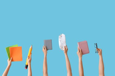 Okul malzemeleri ve mavi arka planda gözlüklü kadın eller.