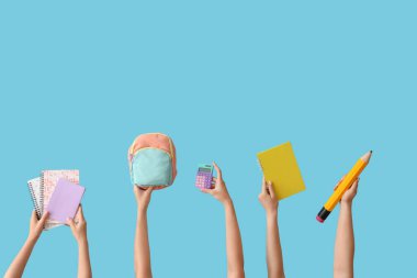 Okul malzemeleri ve mavi arka planda sırt çantası olan kadın eller.