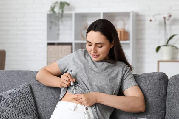 stock image Diabetic young woman using lancet pen on couch at home