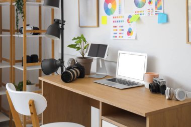 Modern fotoğraf stüdyosunda dizüstü bilgisayarı, renkli tekerlek çizelgeleri ve kameraları olan fotoğrafçı işyeri