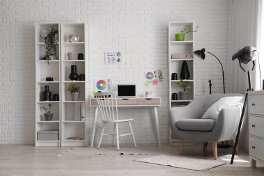 Modern stüdyoda dizüstü bilgisayarlı, renkli tekerlek çizelgeli, koltuklu ve ışıklandırma ekipmanlı fotoğrafçı.