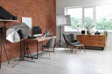 Modern stüdyoda bilgisayarlı, fotoğraf makineli ve ışıklandırma ekipmanlı fotoğraf işyeri