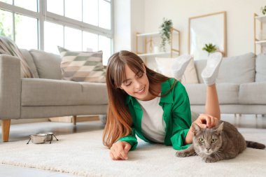 Güzel, genç ve mutlu bir kadın ve sevimli bir kedi evde yerde yatıyor.