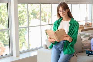 Mutlu bayan öğrenci kitap okuyor ve evde çalışıyor.