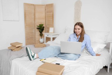 Dizüstü bilgisayarı ve evde ders çalışan yorgun bir kız öğrenci.