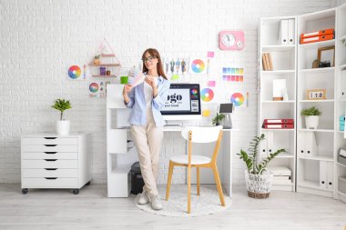 Ofisinde renk paletleri olan kadın grafik tasarımcısı