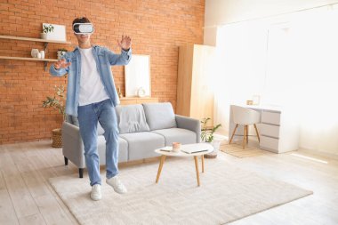 Young man using VR glasses at home