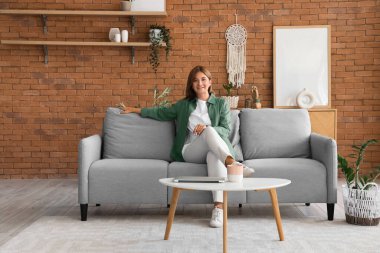 Evdeki gri kanepede oturan güzel kadın.