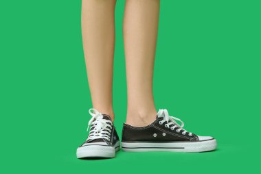 Yeşil arka planda şık siyah ayakkabılı genç kadın bacakları.