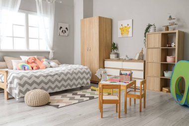 Yatak, dolap ve raf ünitesi olan çocuk odasının içinde.