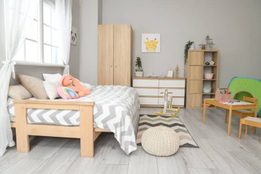 Yatak, dolap ve raf ünitesi olan çocuk odasının içinde.