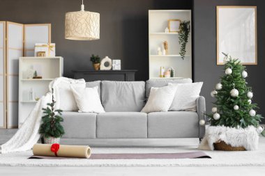Oturma odasının içinde kanepe, yoga minderleri ve Noel ağaçları var.
