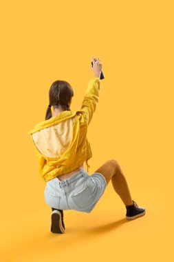 Sarı arka planda sprey kutusu olan genç kız.