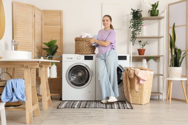 Evde çamaşırları olan genç bir kadın.