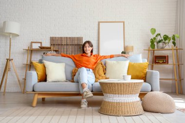 Evdeki kanepede dinlenen güzel genç bayan.