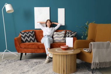 evde koltukta oturan genç ve güzel kadın