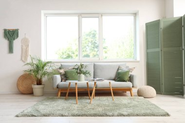 Oturma odasının içinde kanepe, masa ve pencere var.