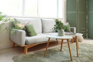 Oturma odasının içinde kanepe, masa ve pencere var.