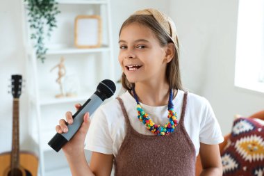 Evde mikrofonlu küçük bir kız şarkı söylüyor, yakın plan.