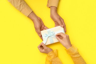 Sarı arka planda hediye kutusu olan çift, üst manzara.