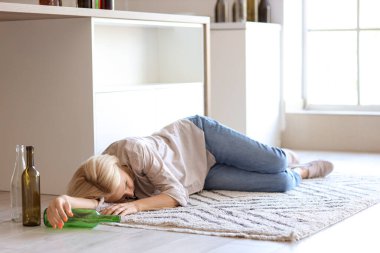 Evde yerde yatan sarhoş, olgun bir kadın. Alkolizm kavramı