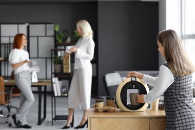 Genç bayan ofiste kahve yapıyor.