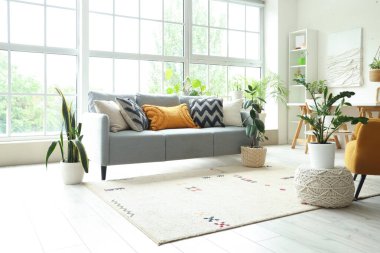 Yeşil çiçekleri, kanepesi ve penceresi olan aydınlık oturma odasının içinde.