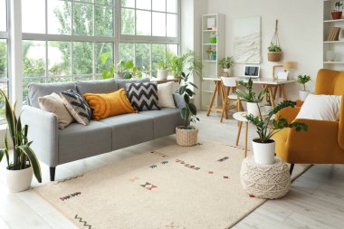 Yeşil çiçekleri, kanepesi ve koltuğu olan bir oturma odası.