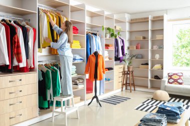 Kadın satıcı butikten elbise alıyor.