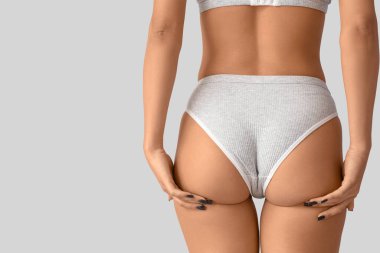 Arka planda selülit sorunu olan iç çamaşırlı genç bir kadın.