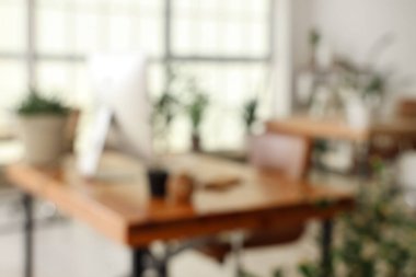 Masalar ve yeşil bitkilerle ofisin bulanık görünümü