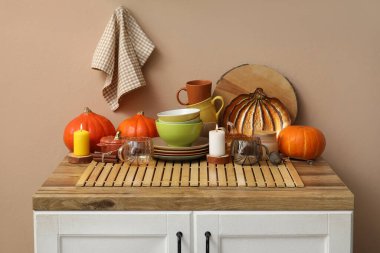 Farklı tabaklar, kabaklar ve yanan mumlarla dolu ahşap masa. Mutfak duvarının yanında.