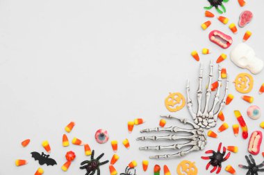 İskelet elli kompozisyon ve gri arka planda Cadılar Bayramı için farklı şekerler