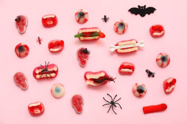 Pembe arka planda Cadılar Bayramı için farklı jöle şekerleri ve dekor içeren kompozisyon