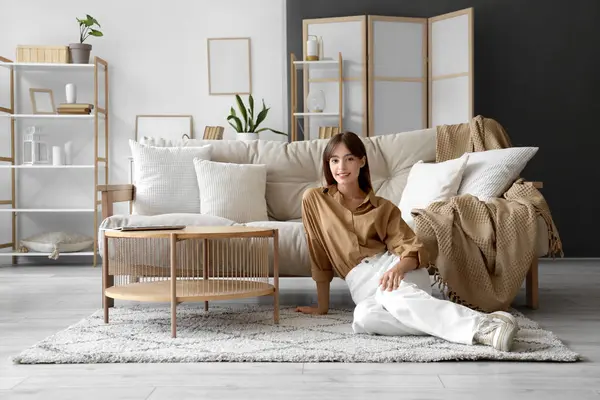 stock image Pretty young woman sitting on floor near sofa