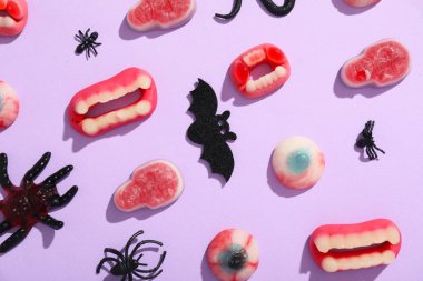 Leylak arka planında Cadılar Bayramı için lezzetli jöle şekerleri ve dekor içeren kompozisyon